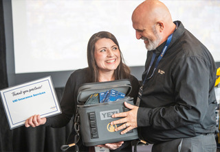 Women receiving a sponsor prize and YETI cooler from man