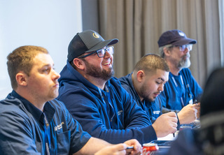 Four men listening to speaker and smiling