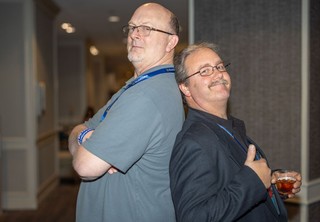 Two professionals posing for photo back-to-back