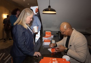 Keynote Speaker Jacob Brown signing autographs in his book at the conference