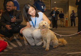 Women kneeling and petting a small dog