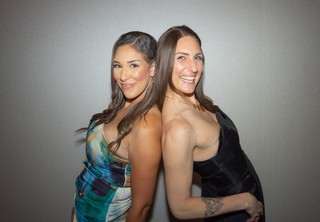 Two women smiling and posing back-to-back