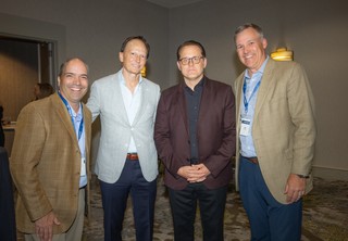 Four businessmen smiling and posing for the camera
