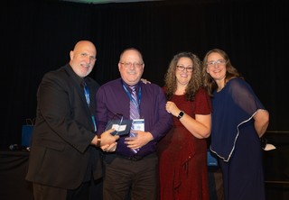 Award recipient posing on stage with three individuals