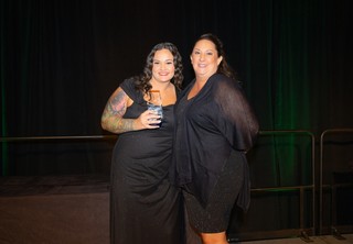 Two women posing on stage with an award