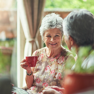 Senior women talking to friend while drinking coffee