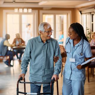 Nurse aiding senior man walking with walker