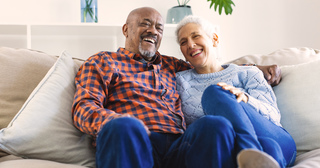 Senior couple sitting on coach and laughing together