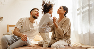 Couple with small child jumping on bed