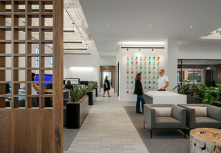 Office entrance with folks working at desks, talking in the entryway, and walking in the hallway