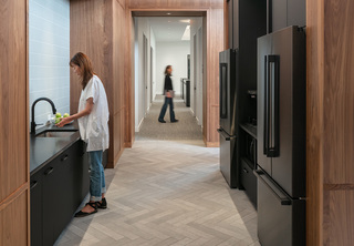 Back kitchen area of office with woman at the sink