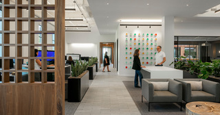 Office with professionals working at open seating, discussing at a tall desk, and walking in the hallway