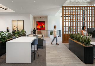 Open office area looking at entrance with people working and walking around